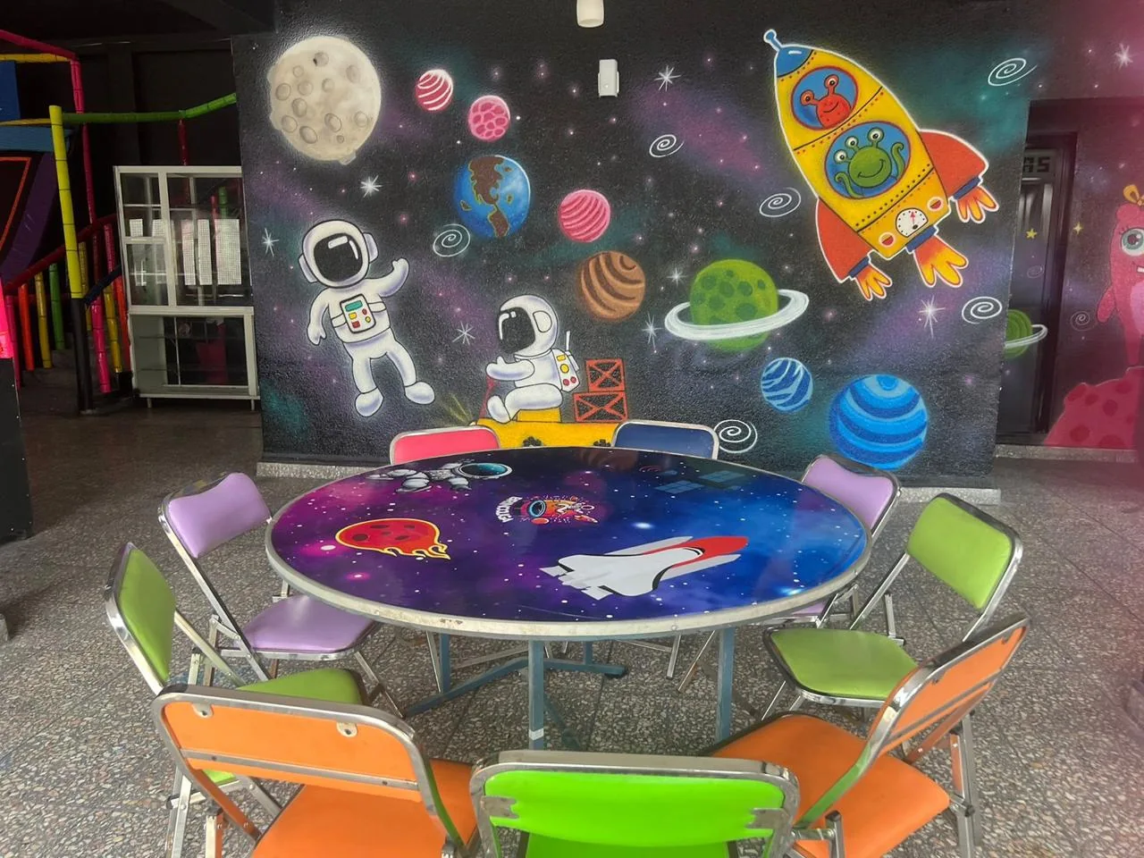 Mesa de celebración con decoración espacial y vista de los brincolines de Brincoliga