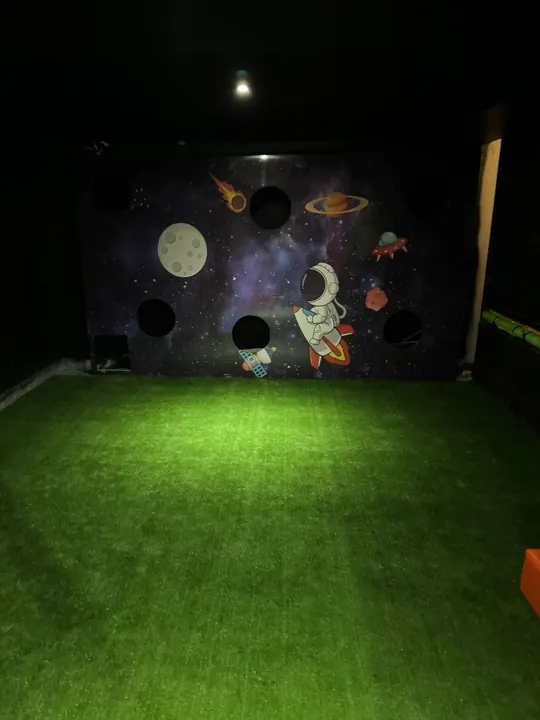 Área verde para juegos con mural de astronauta y planetas